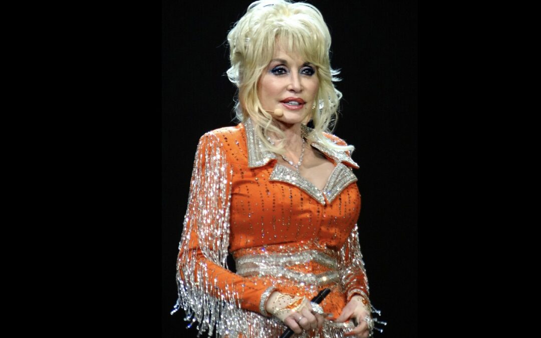 Dolly Parton performing in an orange fringed stage costume