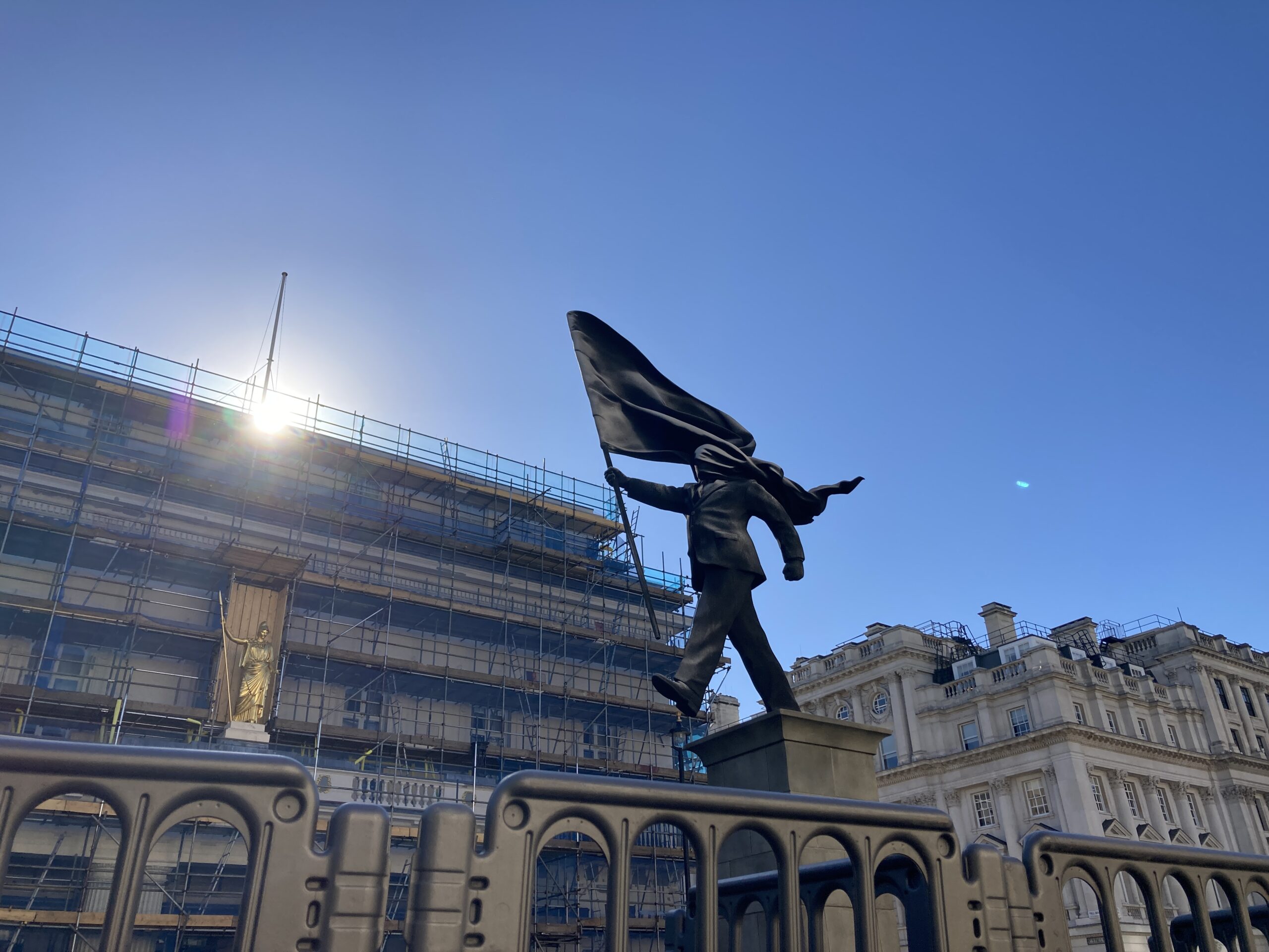 Field: featured image Banksy statue in Waterloo Place showing a suited man stepping from a plinth with a flag covering his face