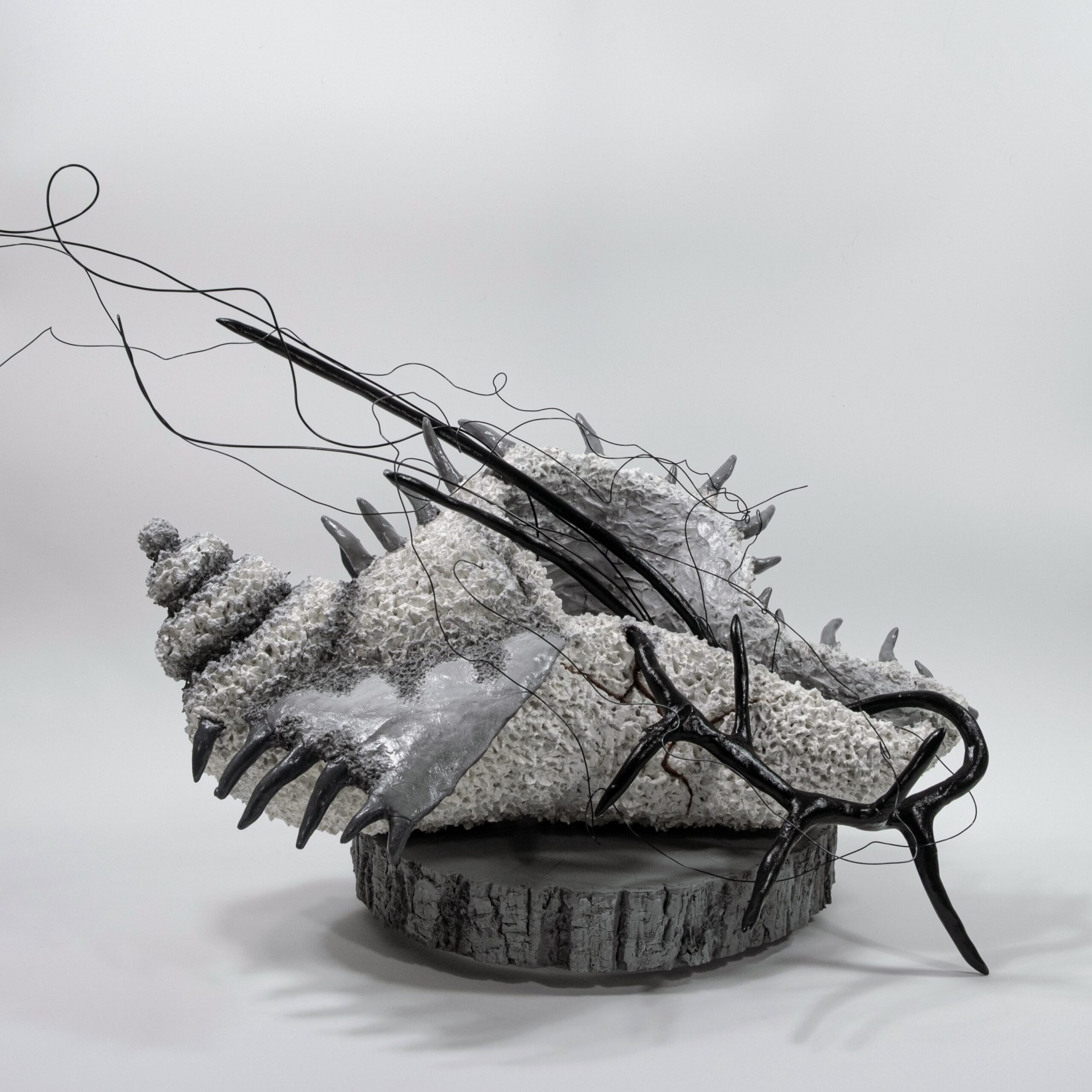 Irina Howard: Giving Shape to the Unseen | ArtTour International A pale textured sculpture on a circular wood base with dark pointed forms and long looping wires extending outward.