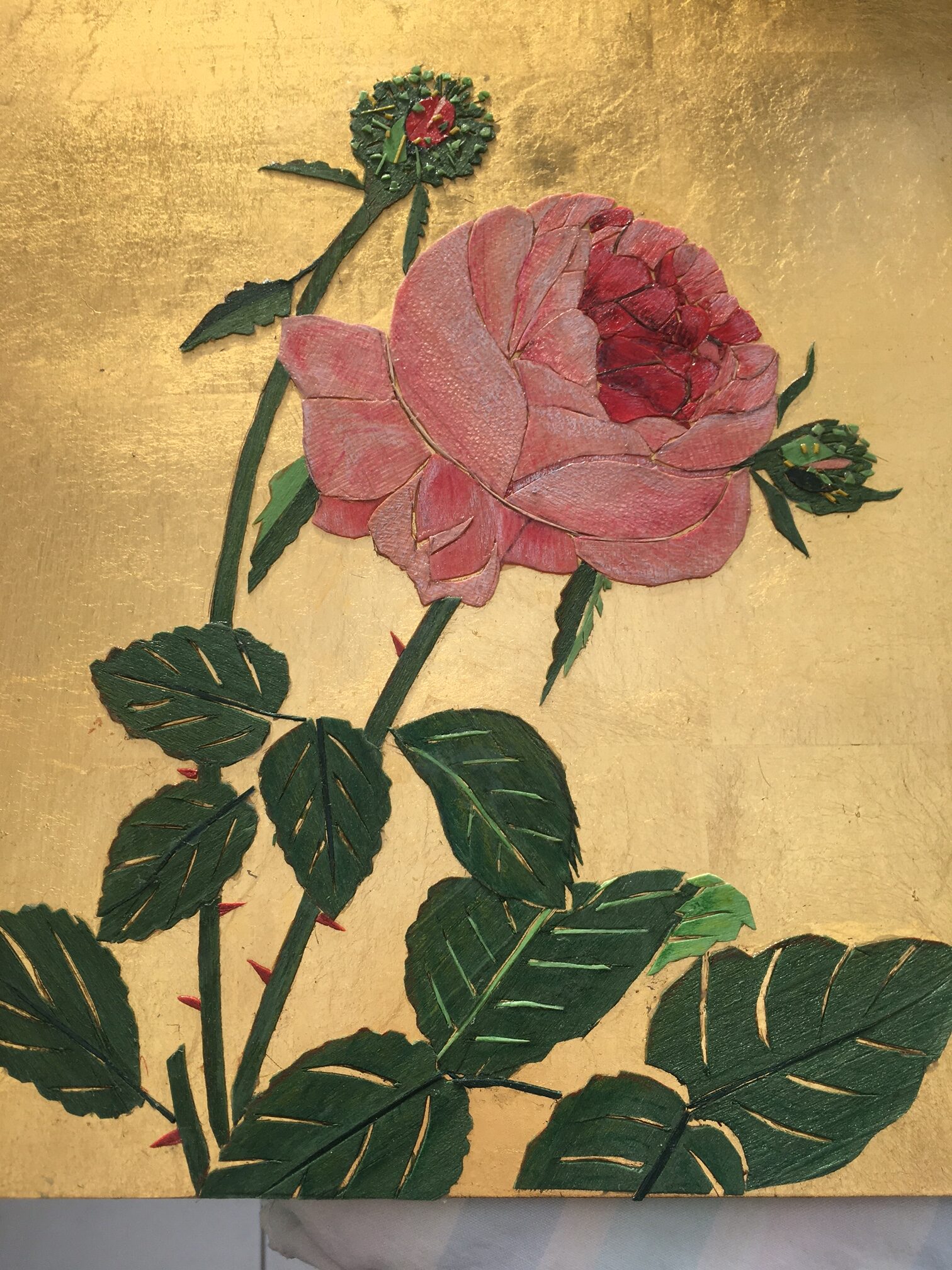 Gabriella Blakey: The Poetry Hidden in Wood | ArtTour International A pink rose and dark green leaves formed from wood veneers against a gold background.