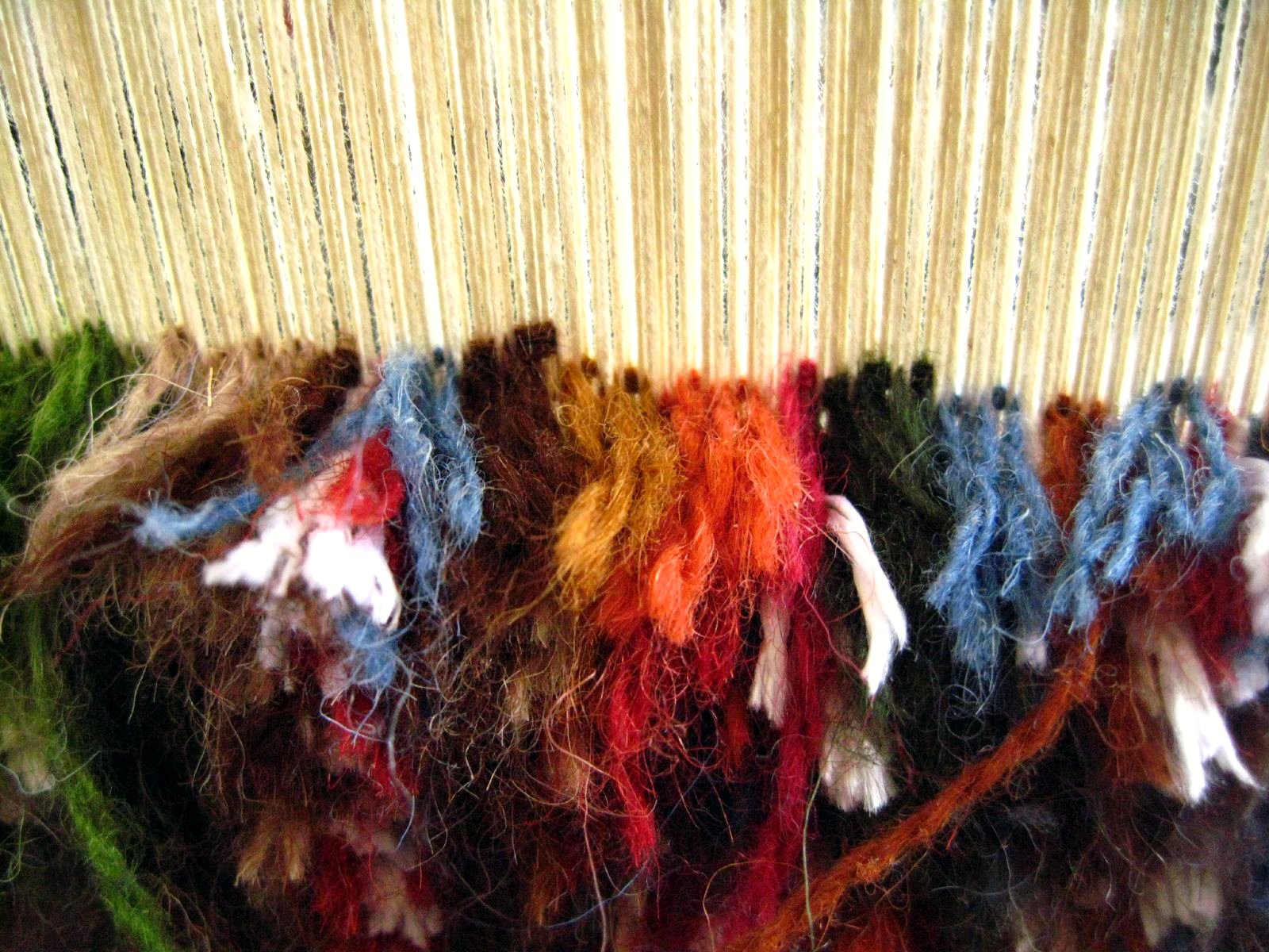 Field: featured image Hands working on a colorful textile at a vertical loom