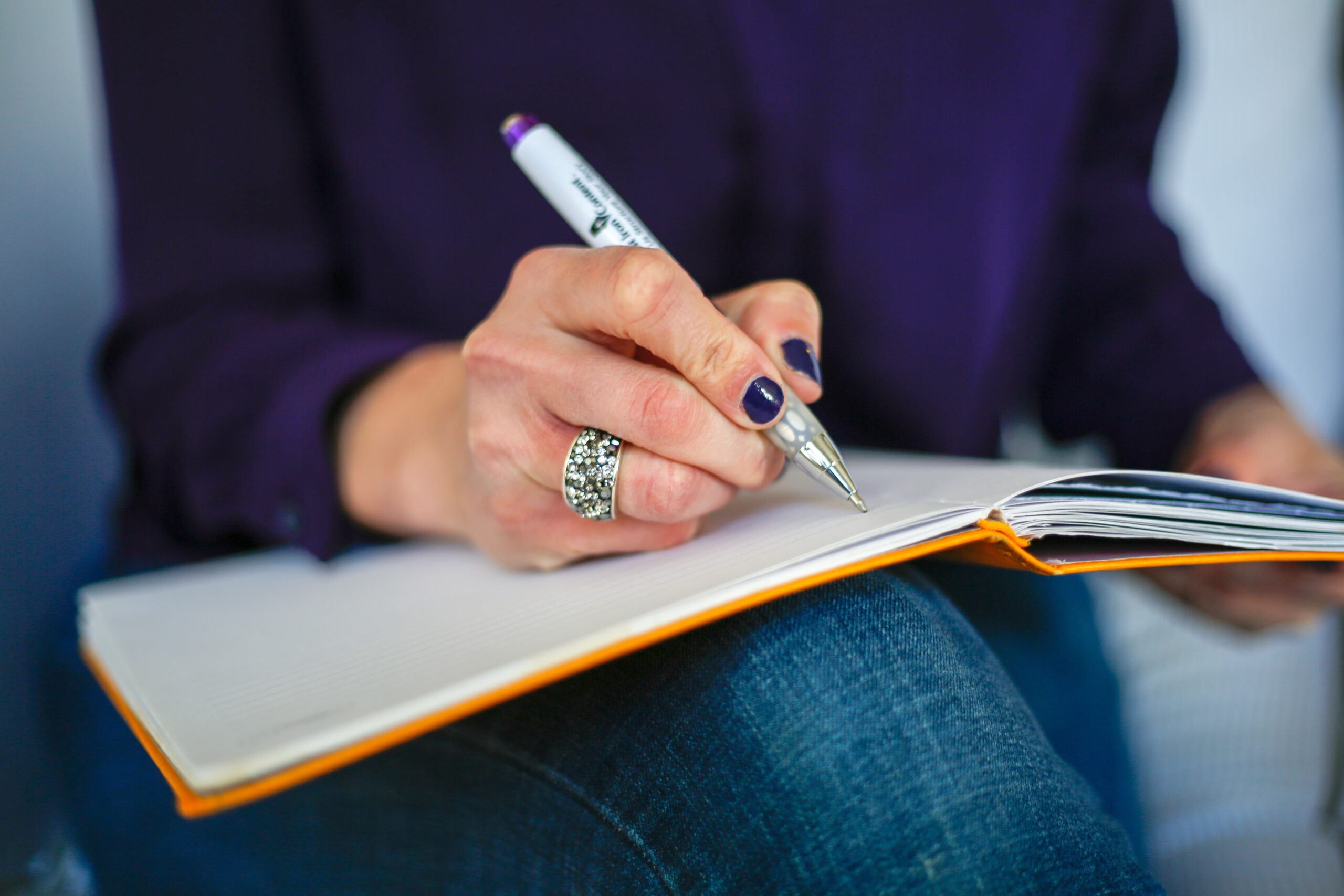 Field: featured image A person writing notes by hand in a notebook beside a laptop